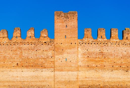 Old brick wall of medieval Italian fortress against the blue sky