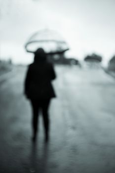 Woman with unfocused backs with transparent umbrella in the rain