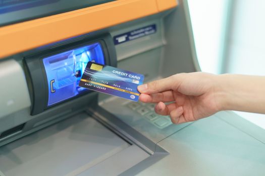 Woman hand  inserting a credit card, into bank machine to withdr
