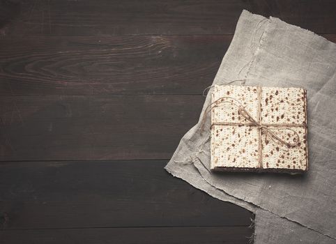 stack of baked square matzoh on brown wooden background