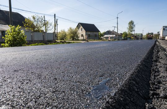 Freshly laid black bitumen asphalt with a high edge to the gravel showing the structure. Laying a new asphalt on the roads. Construction of the road.