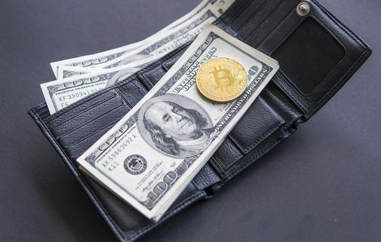 Golden coin bitcoin on us hundred dollars on leather a wallet with full of money. Profit from mining crypto currencies. Miner with dollars and gold bitcoin. Bussiness, commercial. Currency.