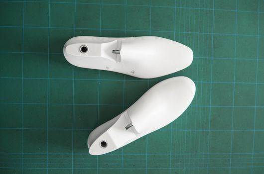 Two white plastic last shoe on rubber secondary cut cutting mat, The equipment used for shoe design.