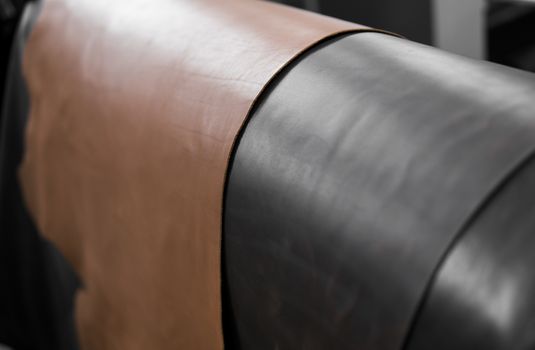 Different pieces of leather in a rolls. The pieces of the colored leathers. Rolls of natural brown and black and other leather. Raw materials for manufacture of bags, shoes, clothing and accessories.