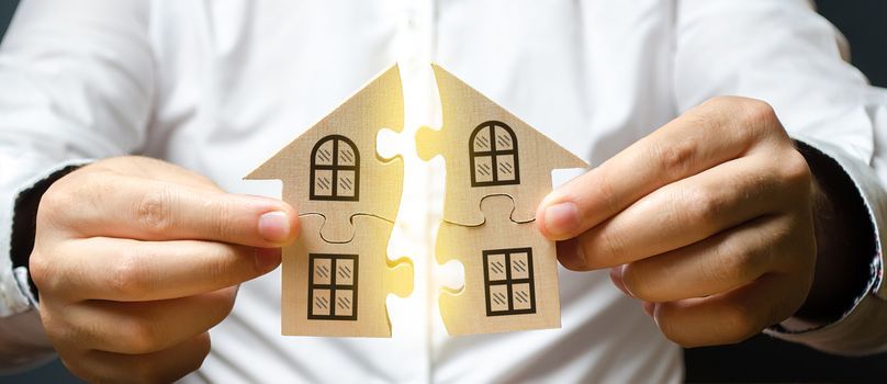 A man connects two puzzles into a whole house above the inscription Mortgage. Construction of your own residential building. Buying a home on credit loan, improvement of living conditions