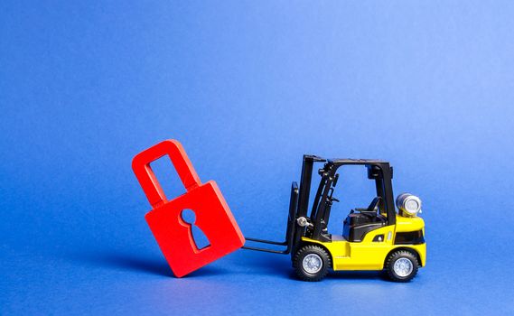 A yellow forklift tilts a red padlock from the road. Bypassing prohibitions and sanctions restrictions, lobbying the interests of industry in government. Loopholes in the laws, overcoming bans.