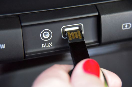 female fingers insert USB memory into usb port on car dashboard