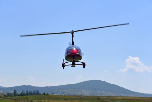 Gyrocopter flying with background of blue sky