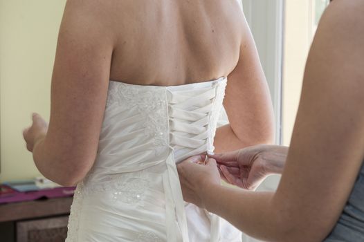 Bride having her dress laced up