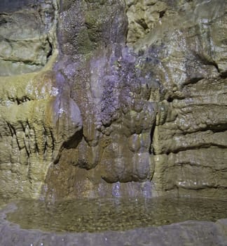 Geological rock formations and water pool in an underground cave