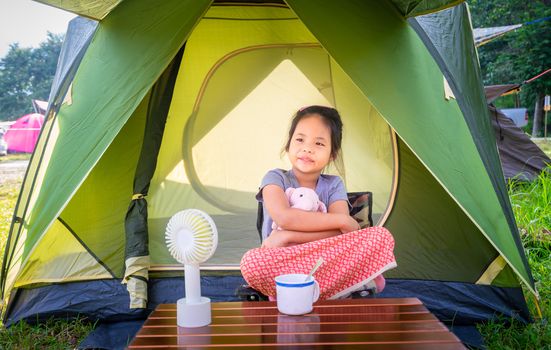 little girl sitting in tent while going camping.The concept of o