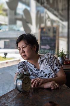 Asian woman waiting in coffee shop cafe with clock