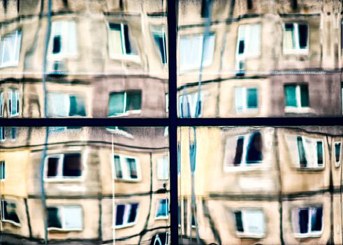 crooked reflection of houses in a glass window