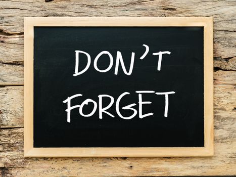 text "don't forget" on black chalkboard with wooden background. meeting remind reminder note concept