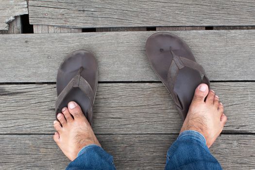 Bare feet of Asian men standing on wooden floor. Broken shoes.