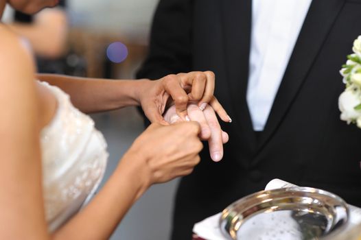 Bride putting a ring on groom's finger