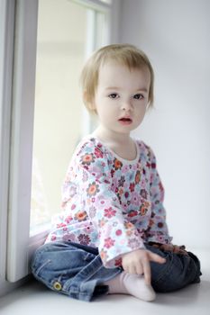 Two years old girl sitting by the window