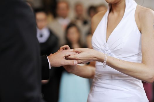 Bride putting a ring on a groom's finger
