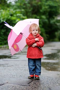 Adorable toddler girl at rainy day in autumn