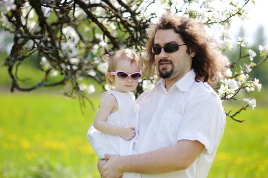 Young father and his daughter in blossoming trees