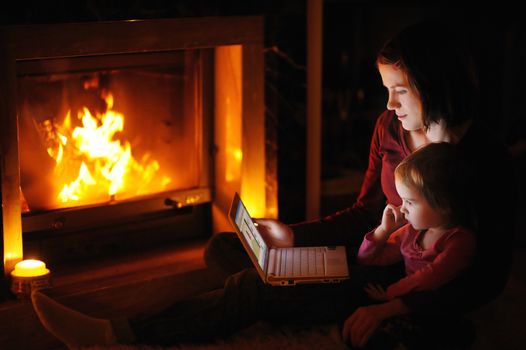 Young mother and daughter by a fireplace