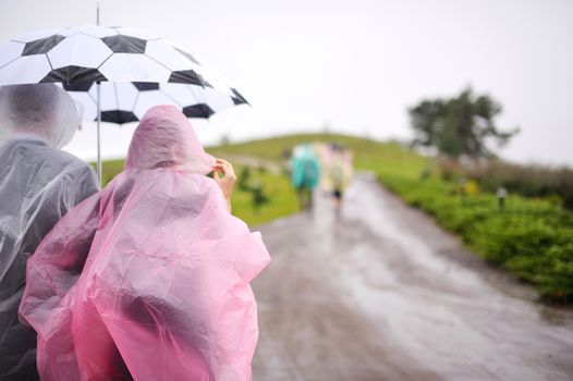 A couple in raincoats under umbrella