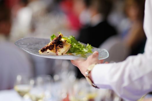 Waitress carrying a plate with meat dish