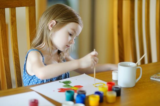 Cute girl is drawing with paints in preschool