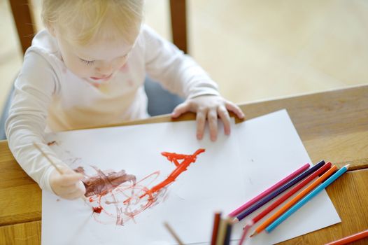 Cute girl is drawing with paints in preschool