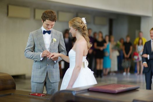 Groom putting a ring on bride's finger