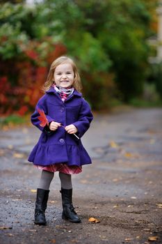 Little girl in a blue coat at autumn