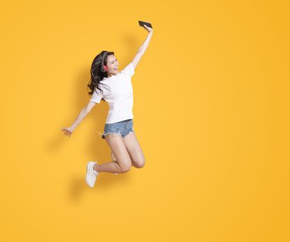  young woman jumping while listening to music on headphones