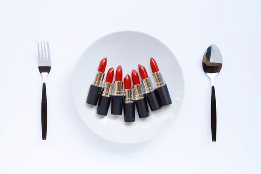 Lipsticks on white dish with fork and spoon on white 
