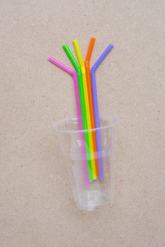 Plastic glass with straws on plywood