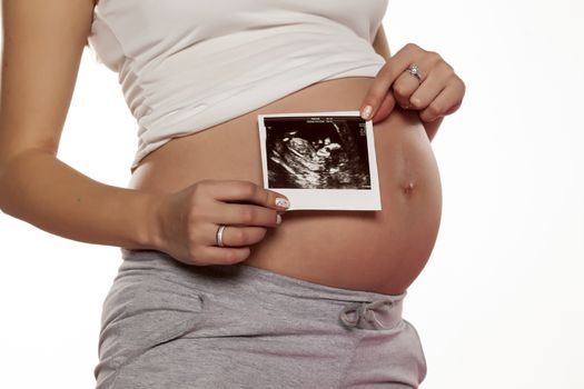 pregnant woman holding the picture of the ultrasound on her bell