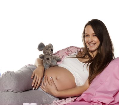 pregnant woman posing on a bed with stuffed toy