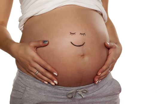Pregnant woman posing with a smiley face on her stomach