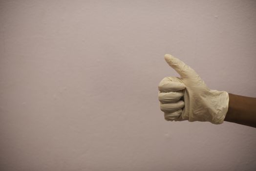 Hand with surgical glove showing thumbs up sign