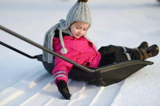 Winter fun: a girl having a ride on a snow shovel