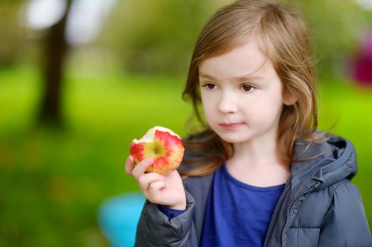 Cute little preschooler girl eating an apple