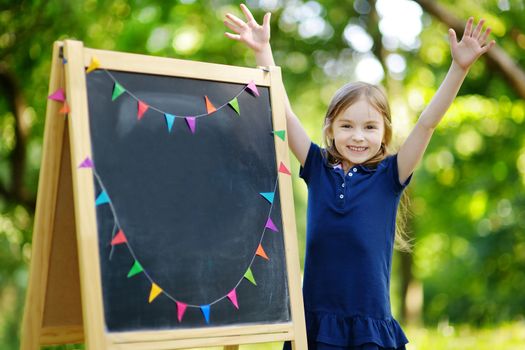 Very excited little schoolgirl by a chalkboard