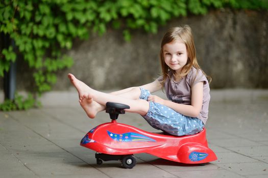 Adorable little girl driving a toy car