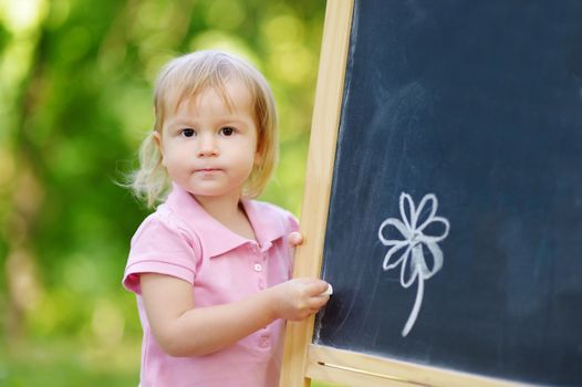 Adorable toddler drawing with a chalk