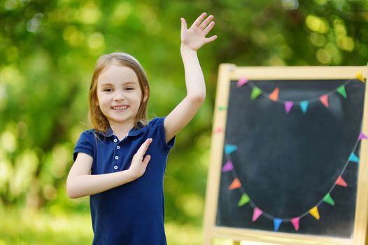 Very excited little schoolgirl by a chalkboard