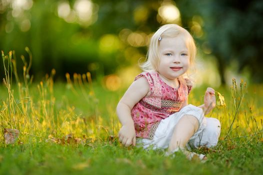 Cute little toddler girl sitting on the grass