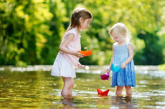 Two little sisters playing with paper boats