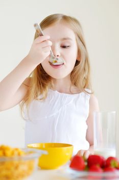 Little girl eating cereal with milk