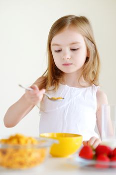 Little girl eating cereal with milk