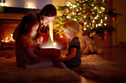 Mother and her daughters opening a Christmas gift