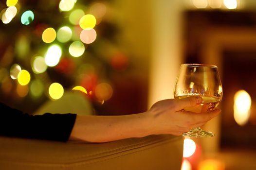 Woman with a drink by a fireplace on Christmas